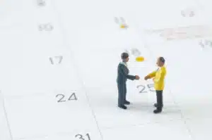 Deux figurines miniatures représentant des personnes en pleines négociations sur un calendrier, illustrant la rencontre entre les syndicats et le ministère de la Fonction publique pour discuter de l’attractivité et des salaires des agents publics.