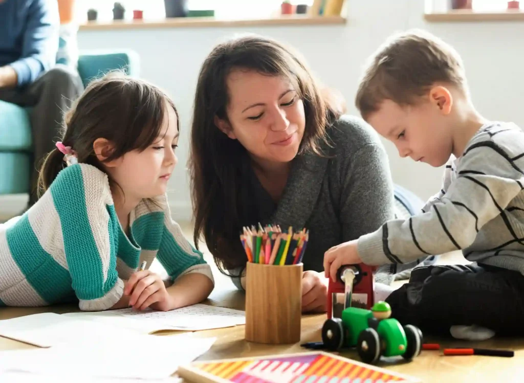 Assistante maternelle encadrant deux jeunes enfants dans un cadre éducatif, illustration de la demande d'attestation d'honorabilité en milieu professionnel.