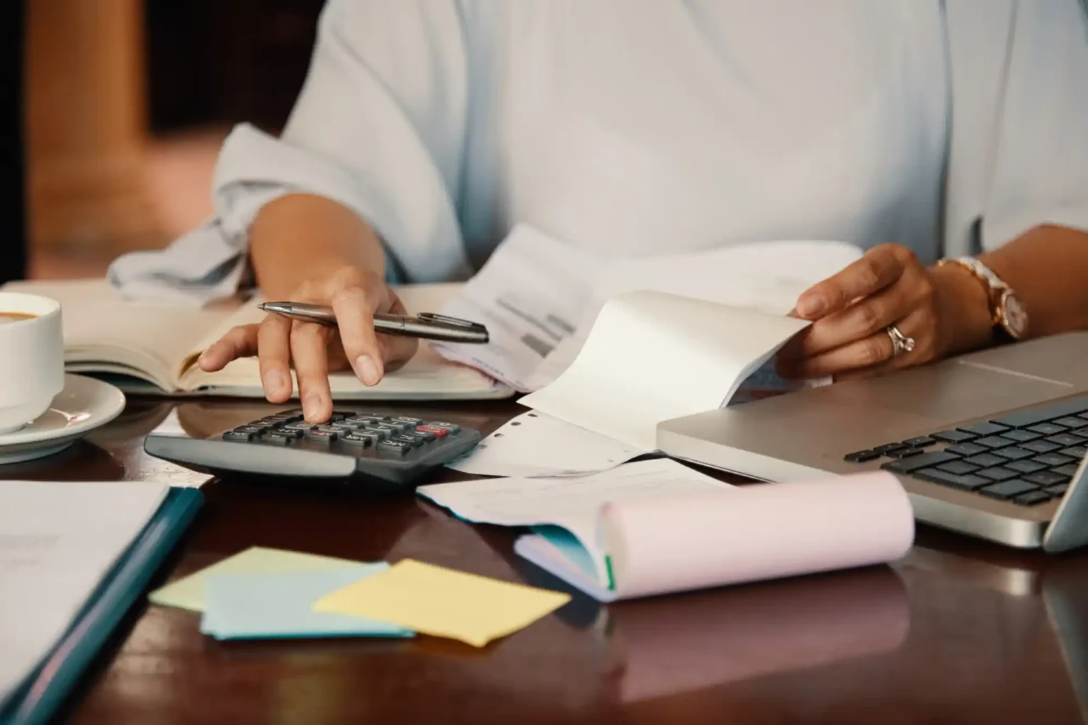Personne remplissant sa déclaration d'impôts avec une calculatrice, des documents administratifs et un ordinateur portable. Il accompagne l'article sur le crédit d'impôt que l'on peut demander en adhérant à un syndicat.