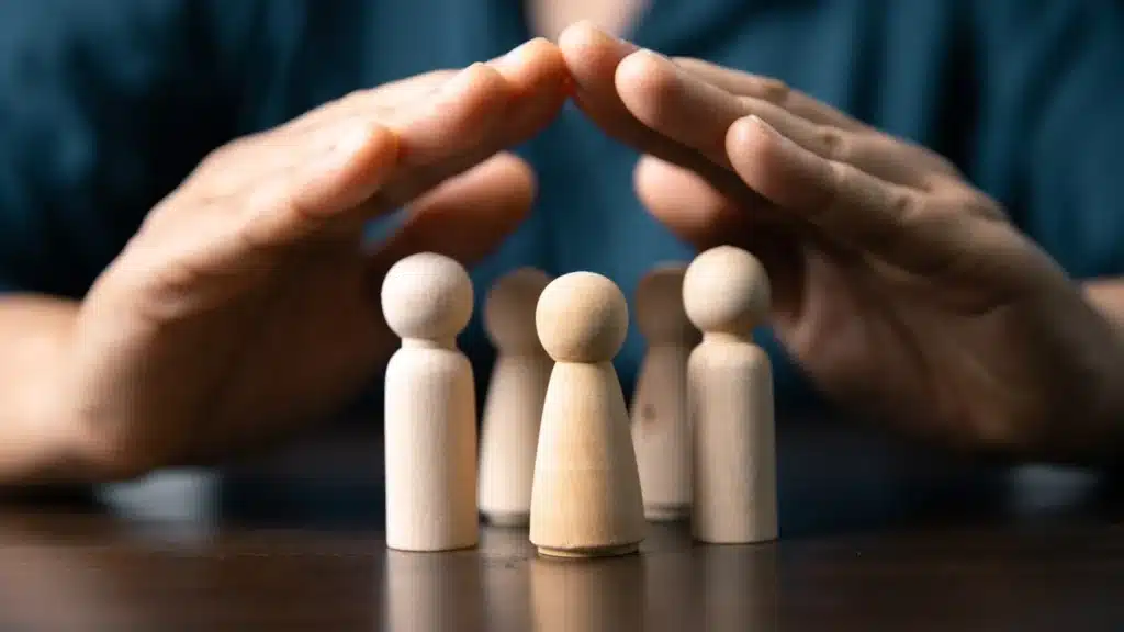 Représentation symbolique de la protection sociale complémentaire avec des figurines humaines protégées par des mains