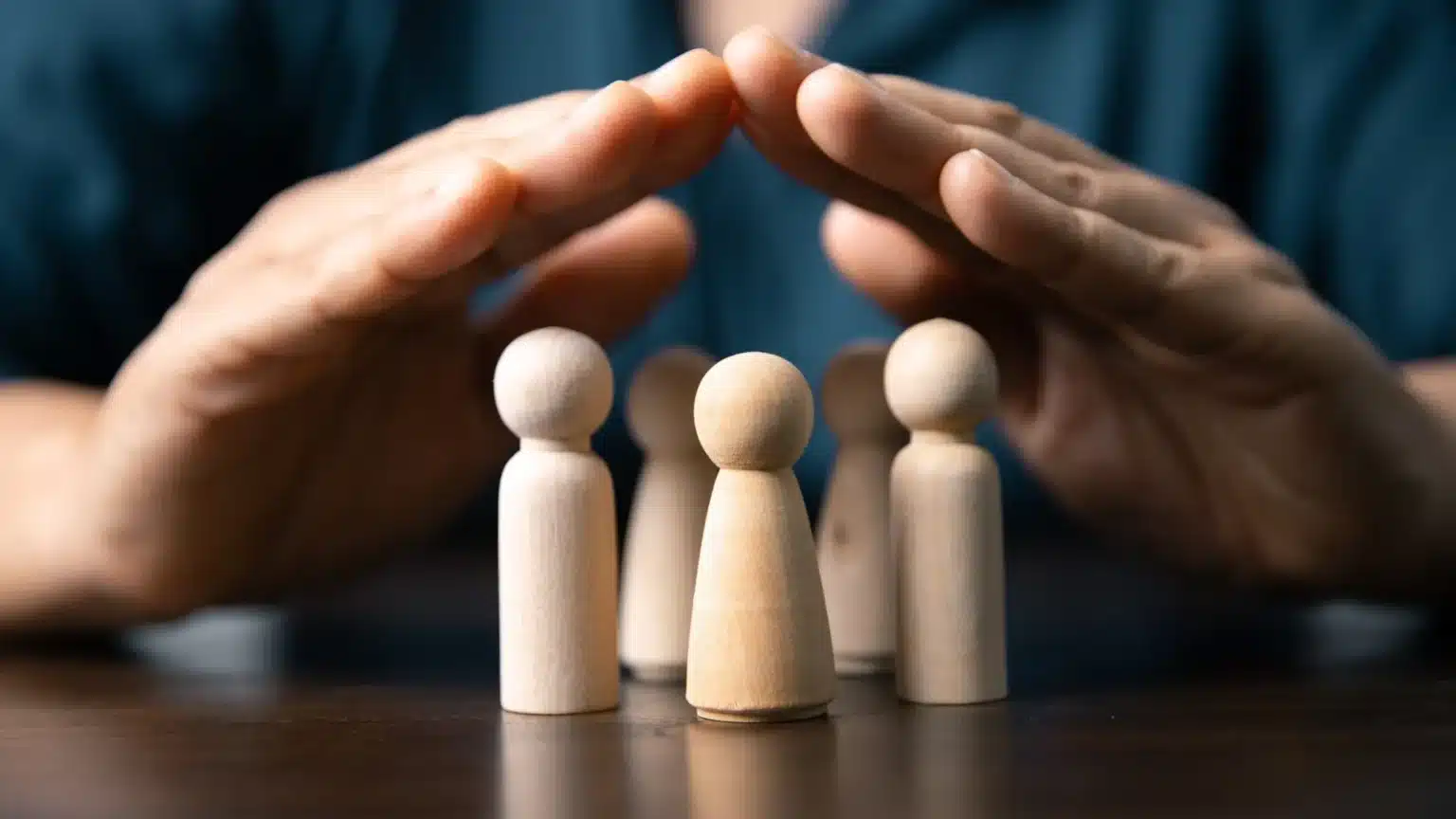 Représentation symbolique de la protection sociale complémentaire avec des figurines humaines protégées par des mains
